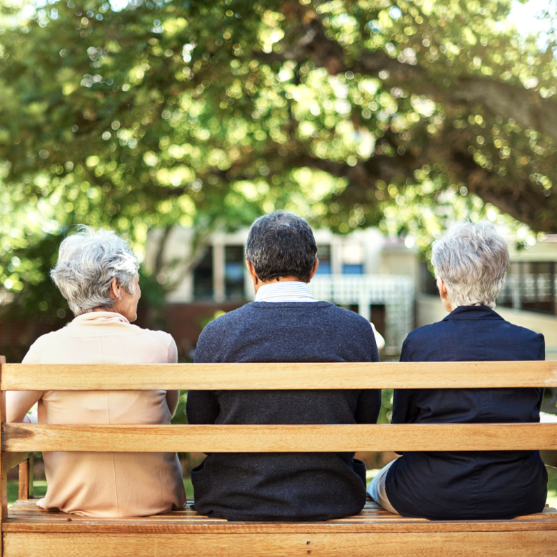 three pensioners on a park bench in a garden